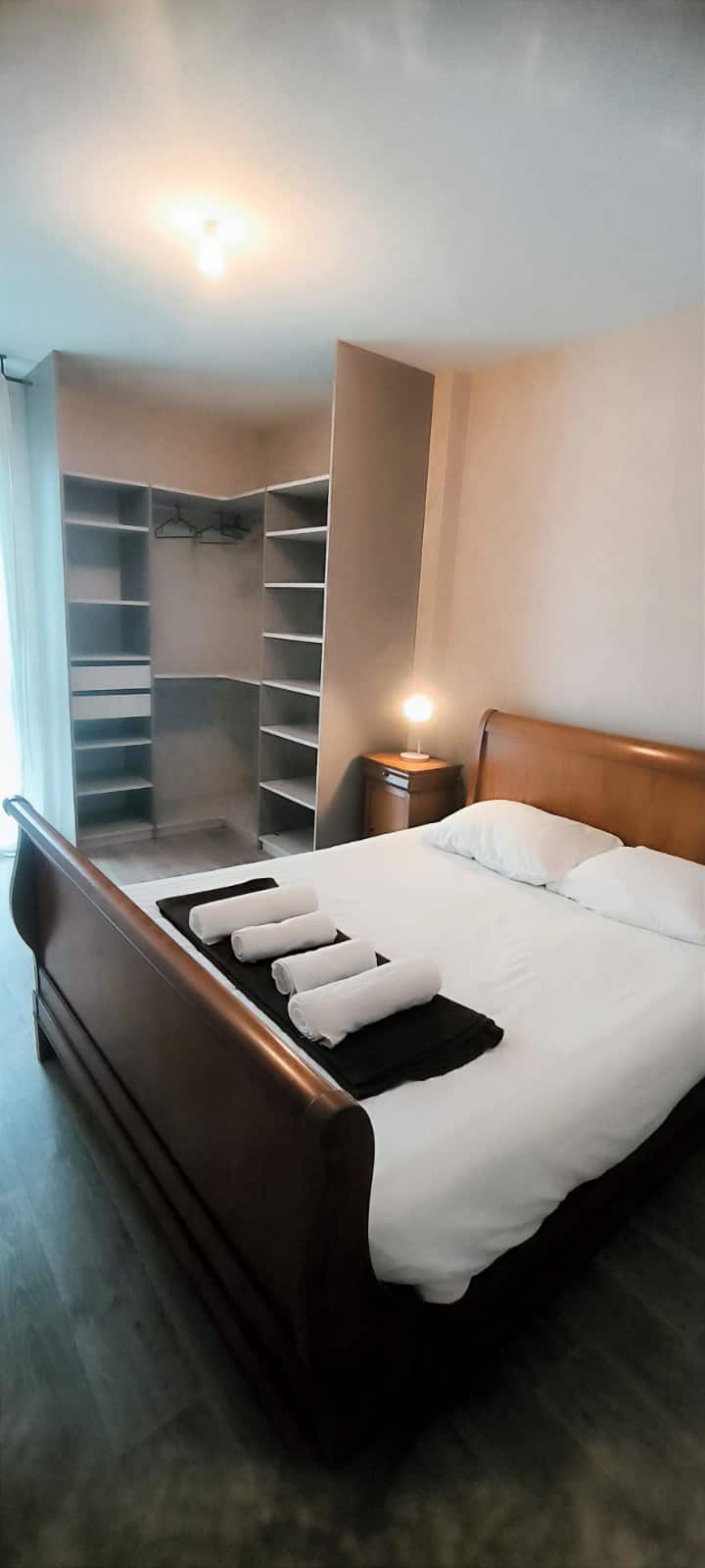 Elegant sovrum med en dubbelsäng och ett omklädningsutrymme. Enkel och ljus inredning, avkopplande och elegant atmosfär.