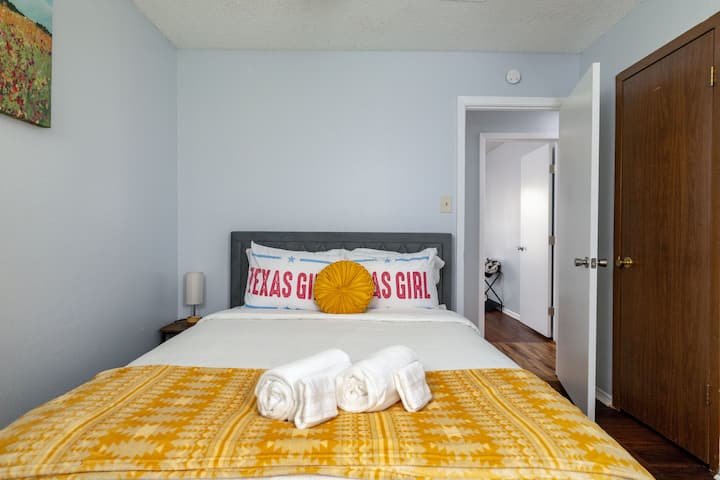 Queen bed with vibrant yellow accents and Texas-inspired decor.