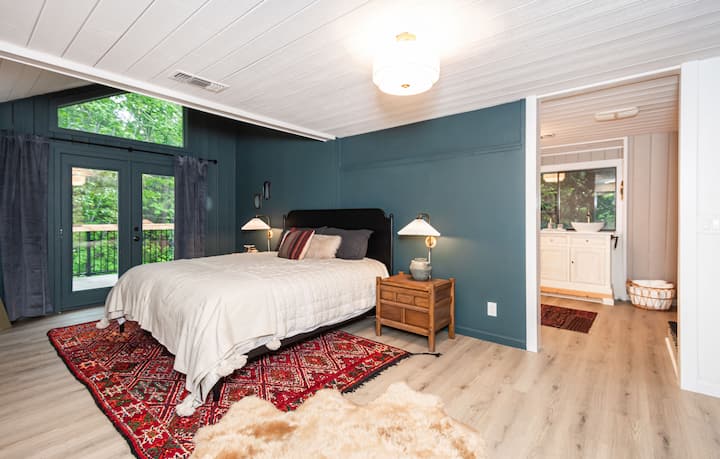 Primary bedroom with forest-green wall and wood stove