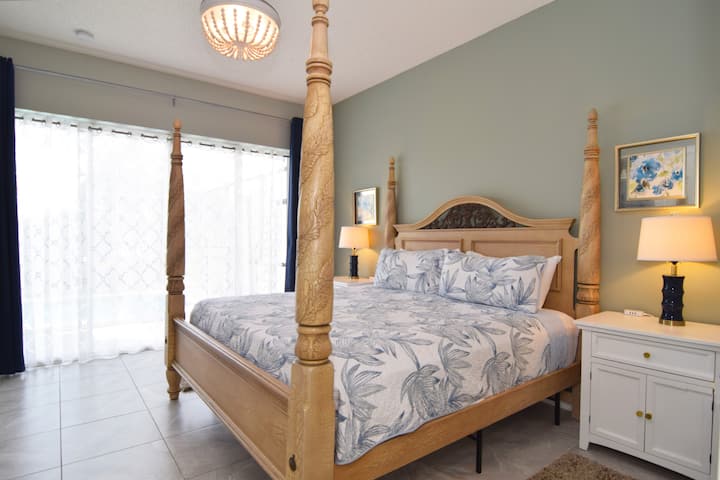 King primary suite with TV, ceiling fan, en suite bathroom and sliding doors out to the pool deck