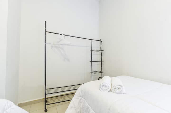 Recámara terciaria con 2 camas individuales, rack para la ropa y clima (AC), ideal para una estancia cómoda y funcional.