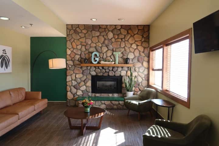 Seating area with stone fireplace, chairs, and side tables