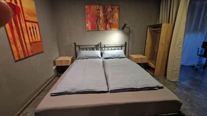 La chambre peut être séparée avec   un rideau opaque de l'espace de travail avec un bureau d'angle réglable en hauteur et une terrasse ; ainsi, l'intimité est préservée, même si l'autre est peut-être dans une conférence de ville/ vidéoconférence.