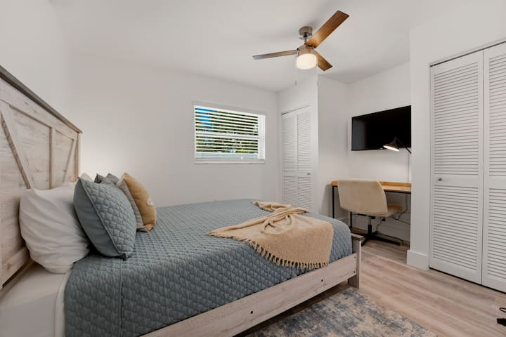Una cama queen en tonos suaves y relajantes crea un ambiente de descanso, combinada con un ventilador de techo para ofrecer una comodidad constante. Un escritorio sencillo ofrece espacio para trabajar o relajarse, y dos armarios le brindan espacio para desempacar y sentirse realmente como en casa.