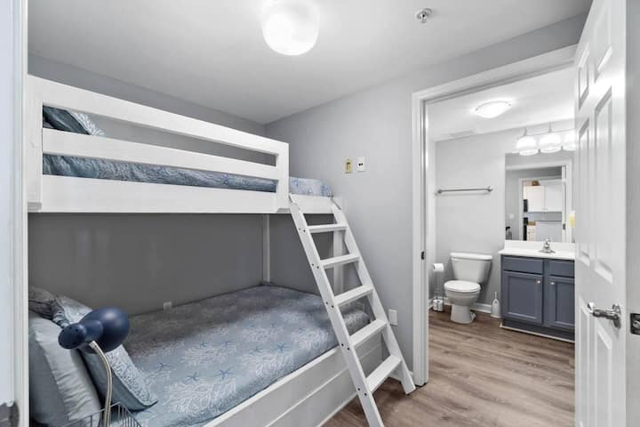 Guest bedroom with single-over-full bunk beds, newly renovated. Includes en-suite walk-in shower and full-size stacked washer and dryer for added convenience.