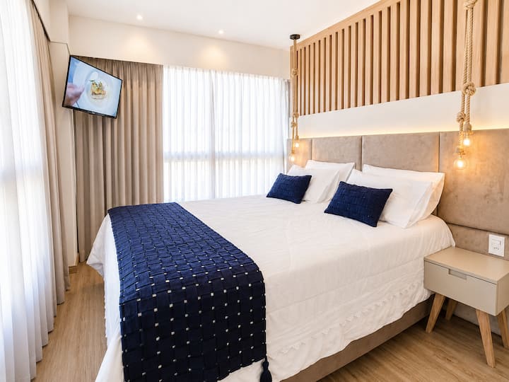 Cama queen com enxoval completo, iluminação suave e cortinas amplas que criam um refúgio confortável e elegante para noites tranquilas em Gramado. ✨️