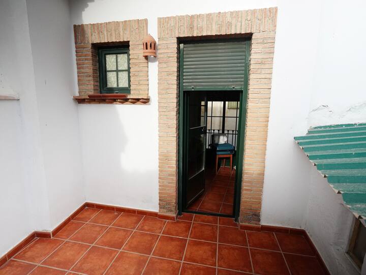 Rincón interior con acceso al patio y suelo de barro: fresco y con aire andaluz.