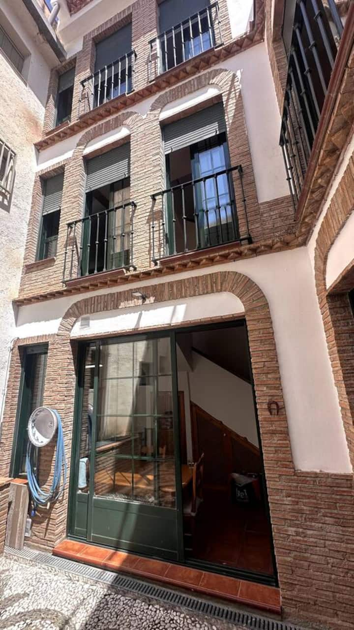 El patio visto desde abajo: tres plantas de balcones de forja hacia el cielo