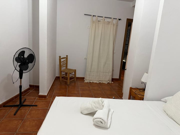 Habitación tranquila con cortinas de lino, silla de enea y ventilador