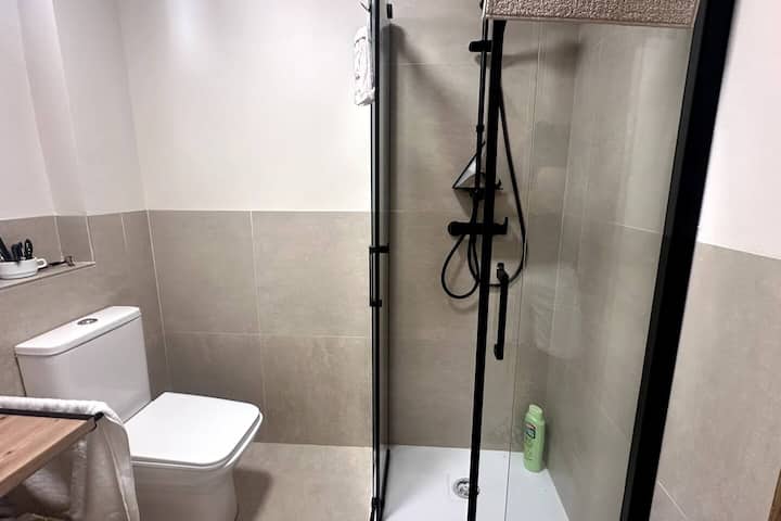 Baño reformado con ducha efecto lluvia y mampara de cristal