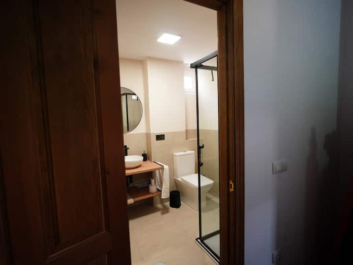 Baño con ducha, lavabo y espejo redondo: moderno y muy cuidado.