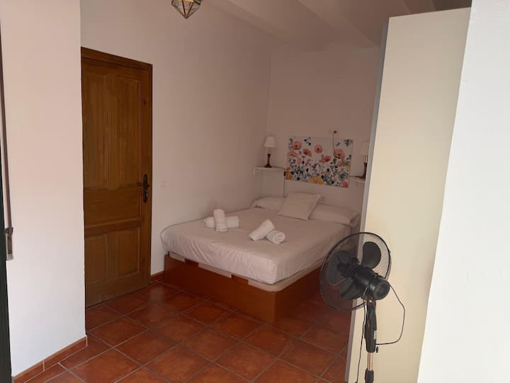 Dormitorio de matrimonio bajo el techo abuhardillado, con lamparitas de lectura