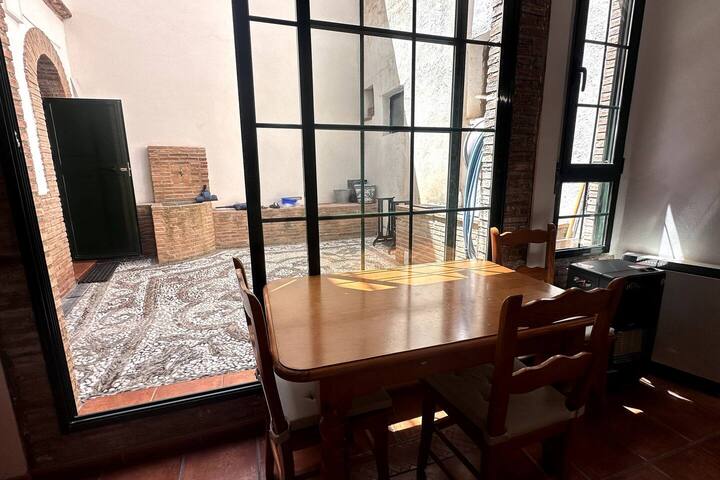 Mesa de madera al sol del patio: desayunos largos con vistas al empedrado