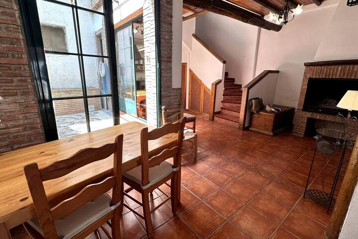 Comedor entre la chimenea y el patio, bajo las vigas originales de la casa