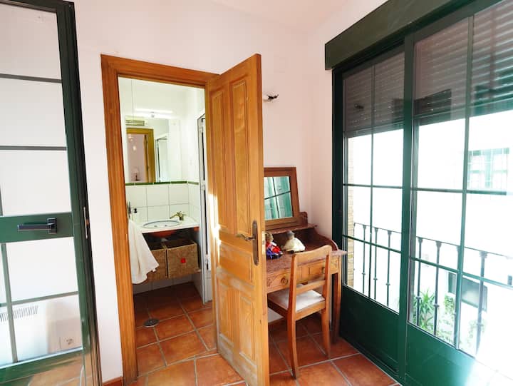 Baño con lavabo de madera visto desde el dormitorio: cómodo y con encanto.