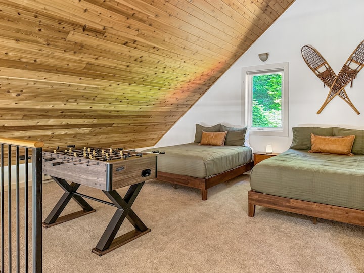 ¡El loft abierto es el lugar favorito de todos los niños! Con dos camas matrimoniales, su propio baño privado, una mesa de futbolín, libros y juguetes, es el espacio perfecto para jugar, relajarse y crear recuerdos juntos mientras se sienten conectados con el resto de la cabaña.
