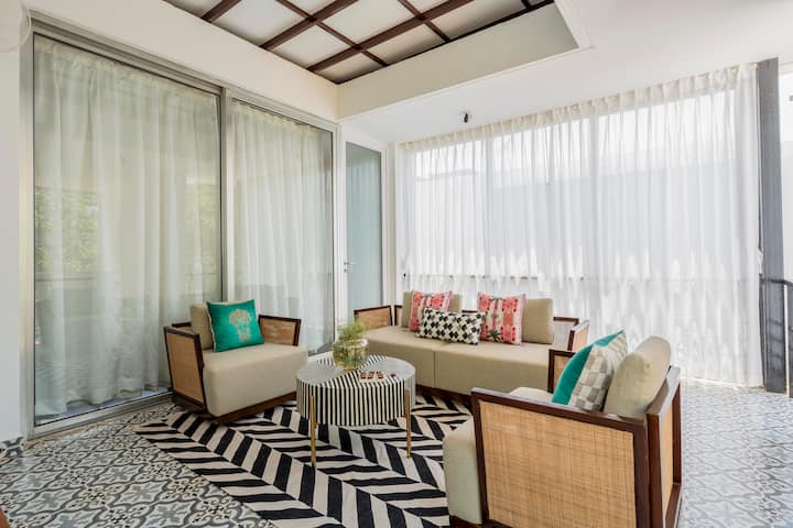 Surrounded by large windows and soft sheer curtains, the space is filled with natural light and offers soothing views of greenery outside