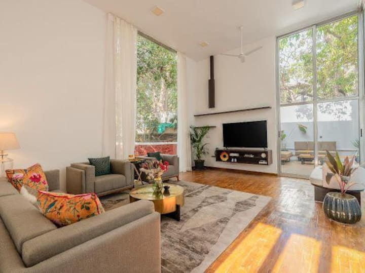 Step into a bright and airy living space designed for comfort and relaxation. With double-height ceilings and floor-to-ceiling windows, this lounge is flooded with natural light and offers serene views of lush greenery outside.