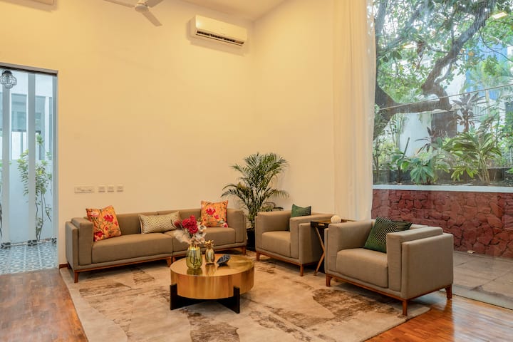 Step into a bright and airy living space designed for comfort and relaxation. With double-height ceilings and floor-to-ceiling windows, this lounge is flooded with natural light and offers serene views of lush greenery outside.