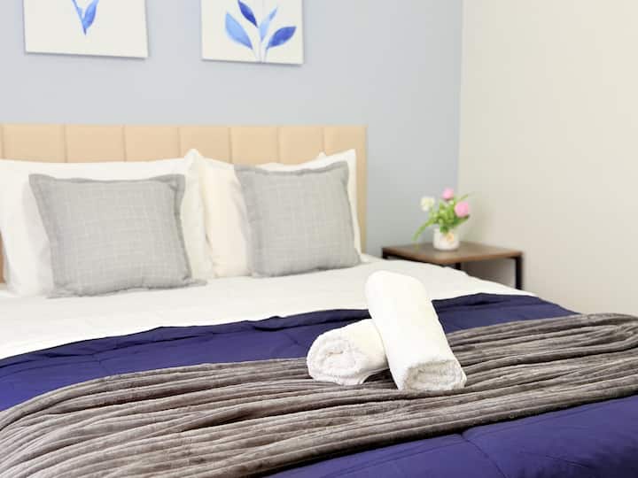 Cama queen composta com lençol, sobre lençol, edredom, cobertor, 4 travesseiros e 2 almofadas.