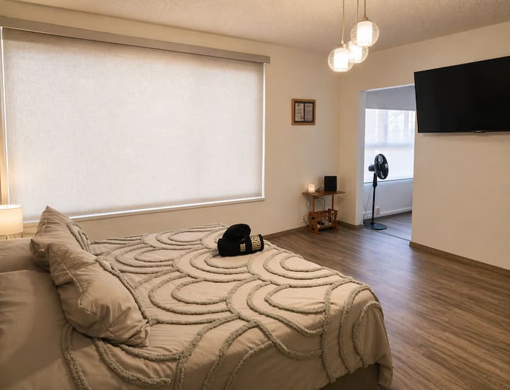 Habitación espaciosa con Smart TV, mobiliario elegante y ambiente tranquilo, ideal para relajarte o disfrutar una noche de descanso.