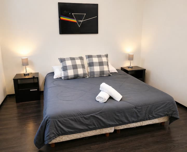 Recámara cómoda y minimalista con cama amplia, iluminación cálida y ambiente tranquilo ideal para un descanso reparador.