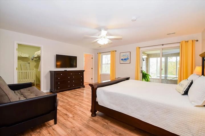 Amplia suite principal con cama king, vestidor, televisor de pantalla plana y acceso a un solárium privado con vista al lago. Cama king, vestidor, suite principal, acceso al solárium, televisor de pantalla plana, pisos de vinilo de lujo de alta calidad, luz natural, dormitorio principal en casa junto al lago.