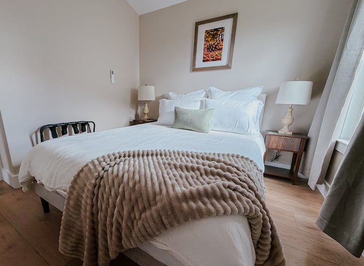 Cozy queen bedroom with layered textures and warm lighting.