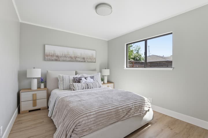 Serene modern bedroom with plush queen bed and bright natural light