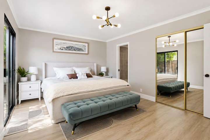 Sunny primary suite with king bed, patio access & mirrored closet.