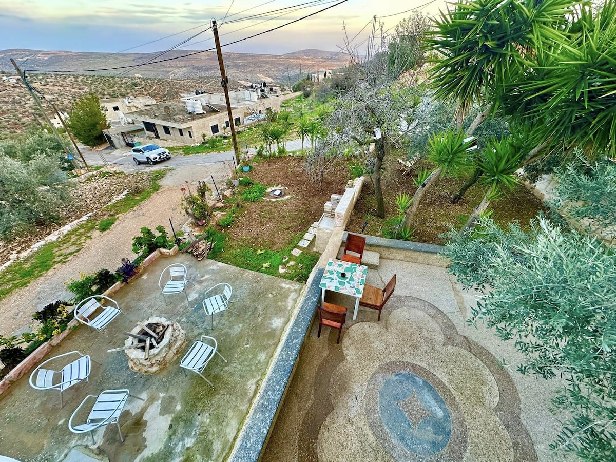 View from above of the terrace, mosaic path and fire pit, with the village road and hills beyond