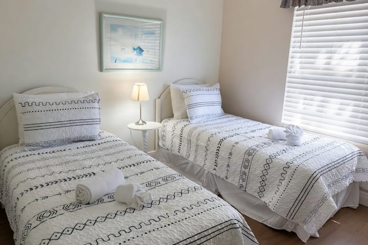 Recámara cómoda con dos camas individuales con ropa de cama a juego, mesitas de noche y lámparas. Ideal para niños, hermanos o huéspedes adicionales.