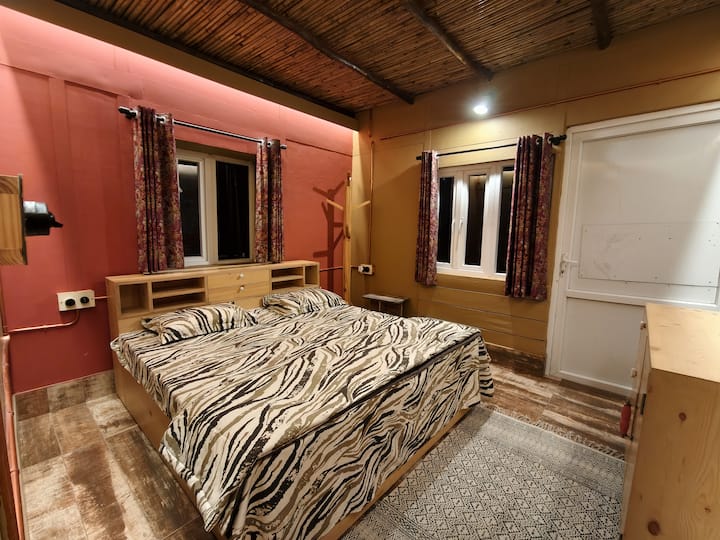 Recámara cálida y acogedora con una cómoda cama king, techo de madera, iluminación suave, espacio de almacenamiento y el encanto apacible de una casa de montaña. Perfecto para disfrutar de noches de descanso después de un día explorando las colinas.