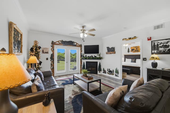 Acogedora sala de estar estilo cabaña con chimenea, TV y puertas francesas panorámicas