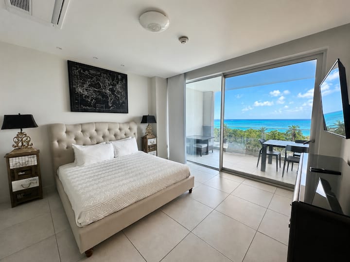 Recámara principal con cama tamaño king, TV, clóset y caja fuerte en la habitación. También tiene un baño privado y puertas corredizas que dan al balcón con vista a Eagle Beach. Las persianas opacas ayudan a mantener la habitación a oscuras para dormir bien.