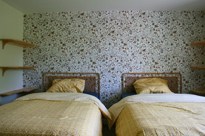 Chambre 2 conviviale avec trois lits simples, dont deux peuvent être rapprochés pour former un lit double selon les besoins. Espace confortable et modulable, idéal pour accueillir familles ou amis dans une ambiance douce et reposante.
