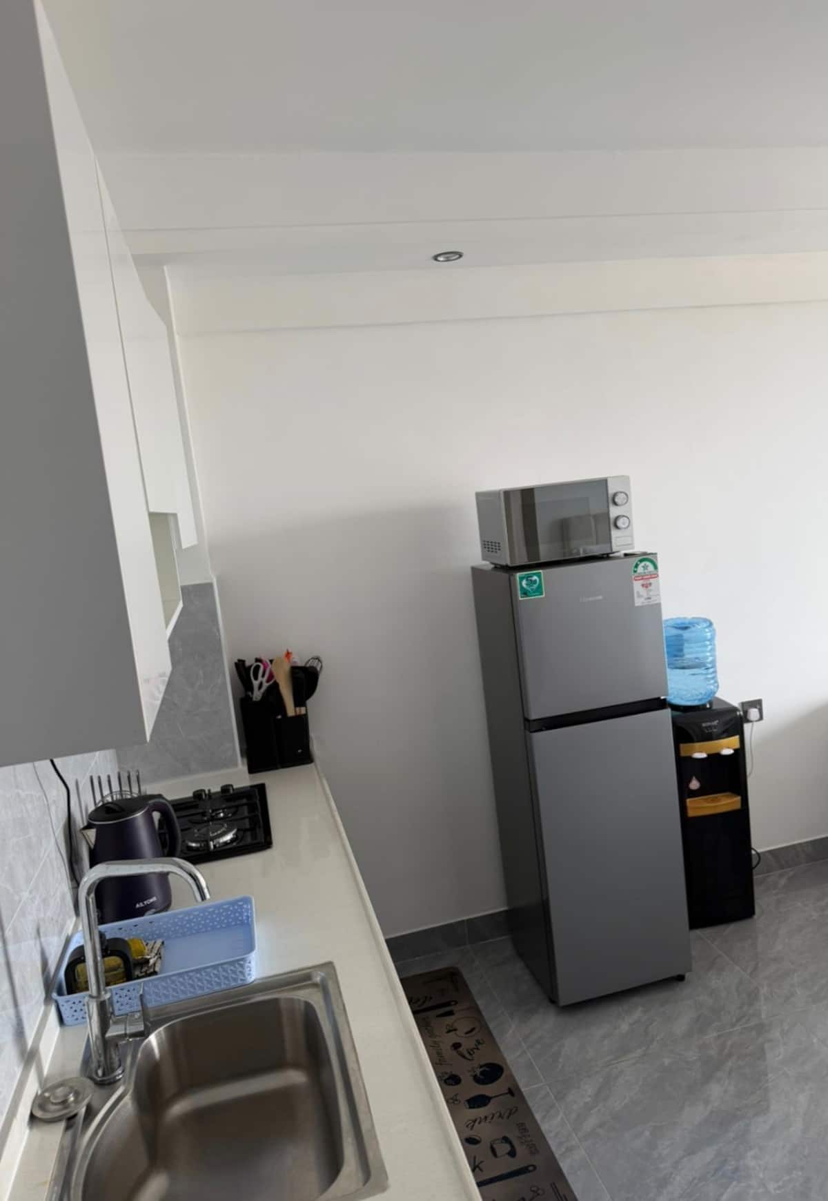 Compact kitchen with fridge, microwave, stove, and kettle