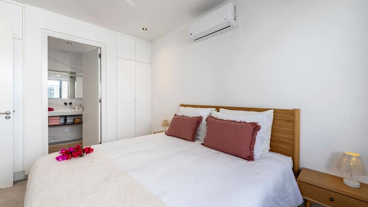 Chambre à coucher calme et confortable avec salle de bain attenante, climatisation et lit parapluie pliable pour un séjour relaxant en famille.