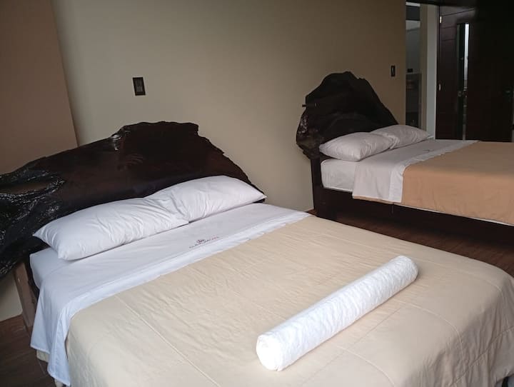Habitación amplia con 2 camas matrimoniales y su servicio higiénico.