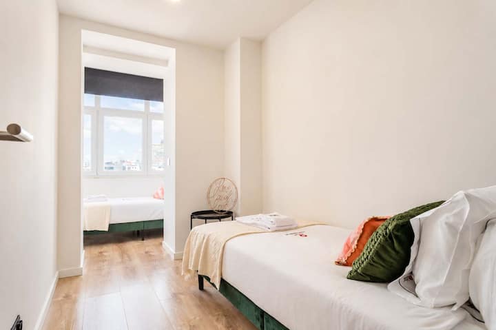 28 · Dormitorio con camas individuales, marco de cama verde y ventana interior · StayInLisbon