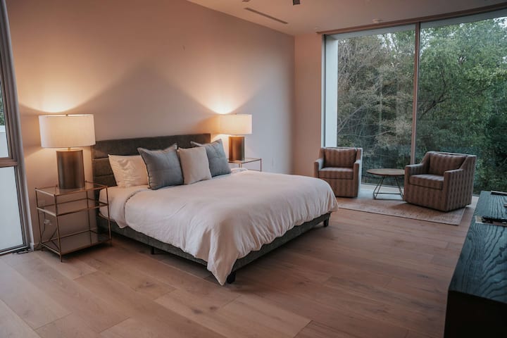 Floor-to-ceiling windows bring the outdoors in, creating a peaceful, private escape surrounded by greenery.