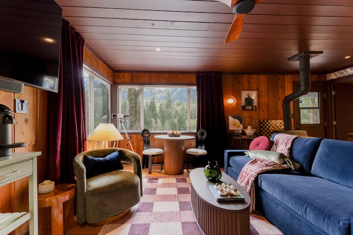 Espacio habitable cálido y de diseño vanguardista, con interiores de madera noble, la calidez de una estufa acogedora y vistas apacibles a las montañas. Un sofá cama queen de felpa para huéspedes adicionales.