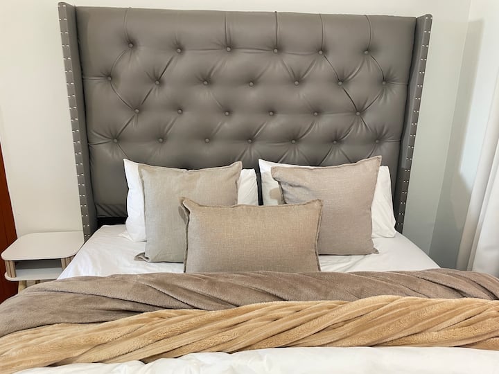 Relájate en una cómoda cama tamaño queen con ropa de cama de primera calidad y almohadas suaves para disfrutar de una noche de sueño reparador.