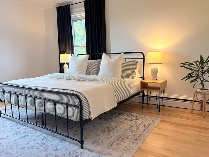 Este dormitorio es el más grande de los tres ubicados en el nivel superior. Cuenta con una acogedora cama tamaño king equipada con dos mesitas de noche y lámparas con capacidad de carga electrónica. Hay dos ventanas grandes en esta habitación con cortinas opacas.