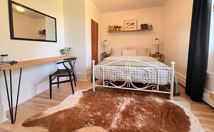 Este dormitorio está ubicado al final de un largo pasillo en el nivel superior y cuenta con una acogedora cama tamaño queen, dos mesitas de noche con lámparas que tienen puertos de carga para teléfonos incorporados.