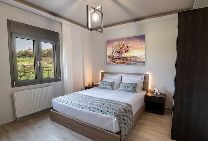 Recámara con una (1) cama king (1.90 × 2.00 m), tomacorrientes, cabecera, almohadas, clóset, área de trabajo, tabla de planchar, caja fuerte y ventana con vista