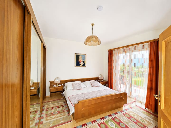Dhomë gjumi kryesore e gjerë me një krevat dopio të rehatshëm, mobilje elegante prej druri, gardërobë të madhe dhe akses të drejtpërdrejtë në ballkonin privat. Drita e ndritshme natyrale, ngjyrat e ngrohta dhe një atmosferë paqësore krijojnë vendin e përkryer për t'u çlodhur dhe për t'u rehatuar.