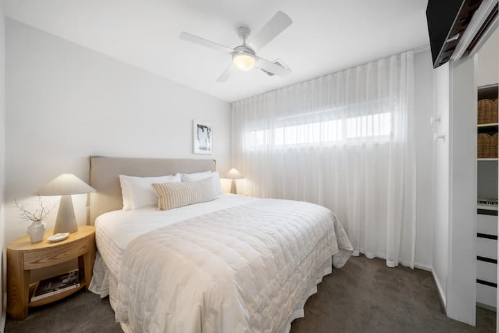 Retreat to the primary bedroom, where a king bed, private TV, ceiling fan and soft layered linens create a peaceful space to unwind at the end of the day.