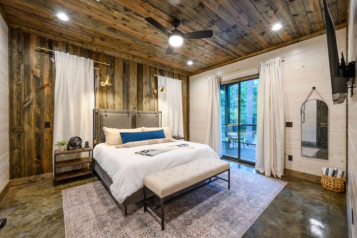 Master bedroom with a king bed, wood accent wall, and sliding doors to a deck.