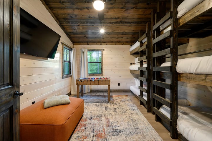 Spacious kids bunk room with built-in wooden beds and a foosball table for fun.
